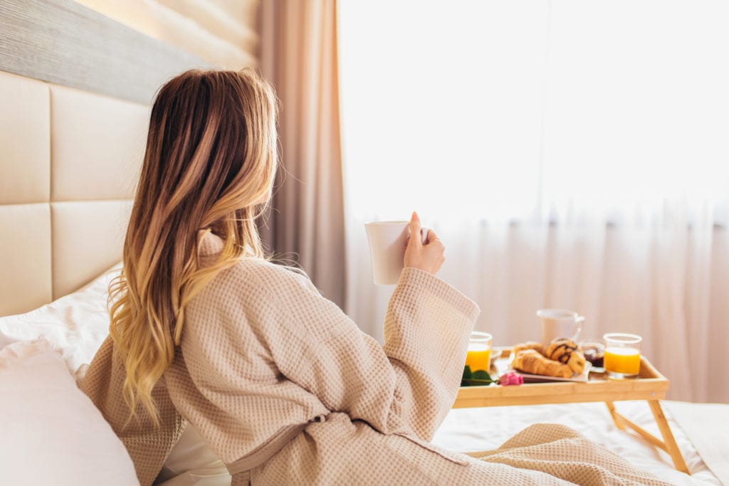 Beautiful woman laying and enjoying, breakfast in bed