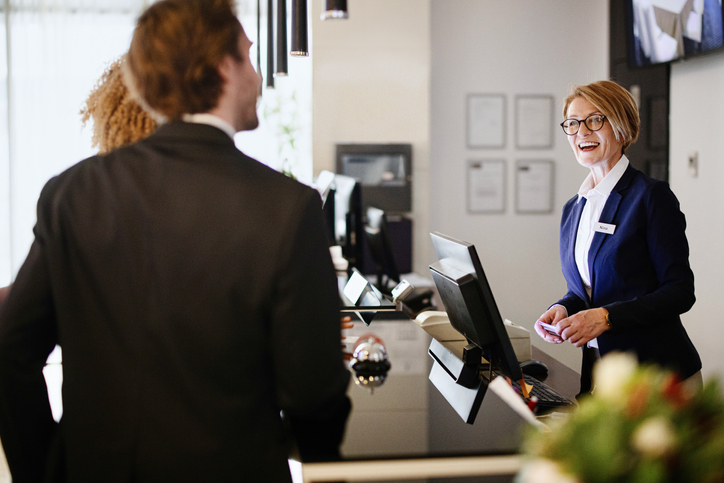 female front desk receptionist checking in guests while promoting new hotel opening