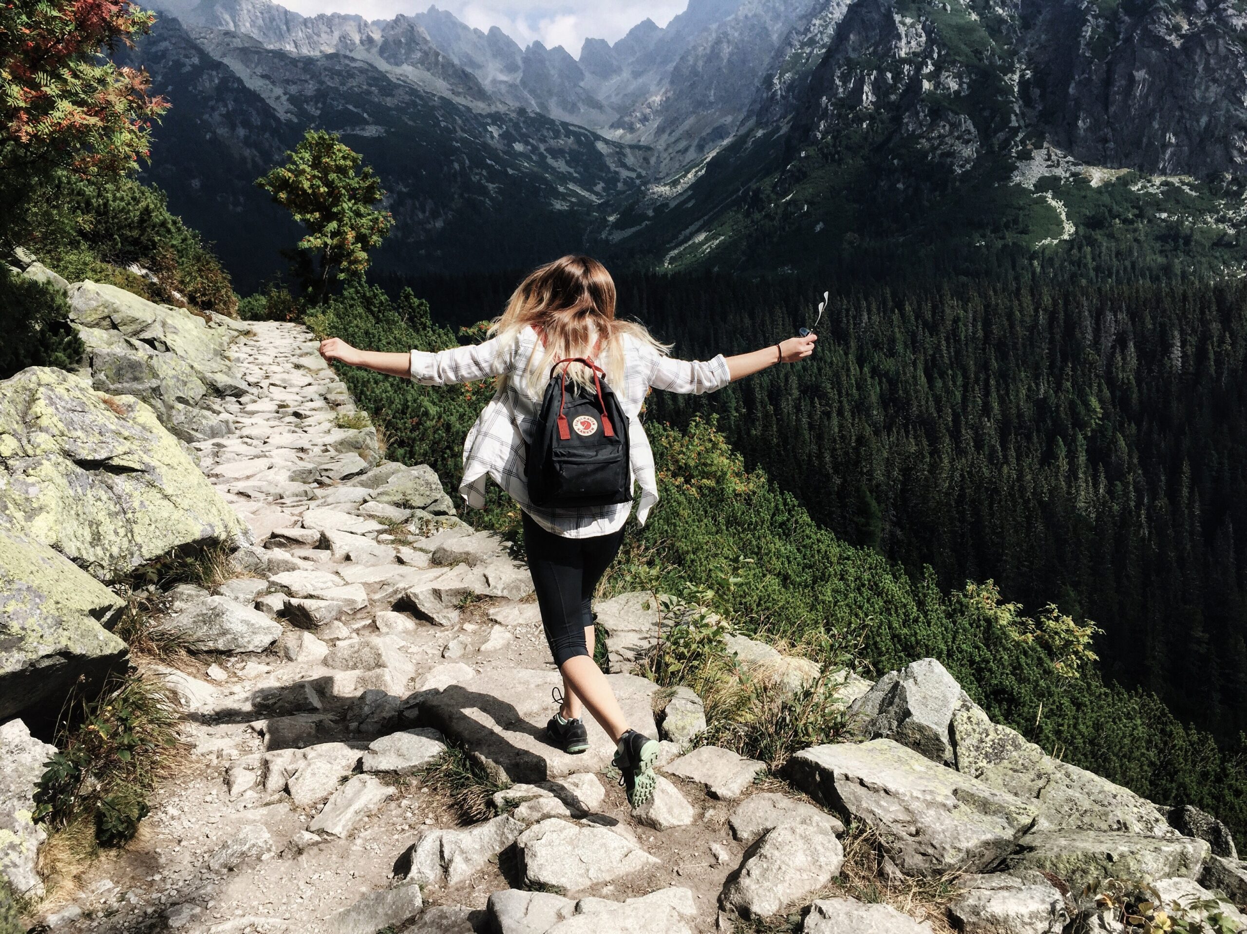 woman hiking along mountainside during her wellness travel trip