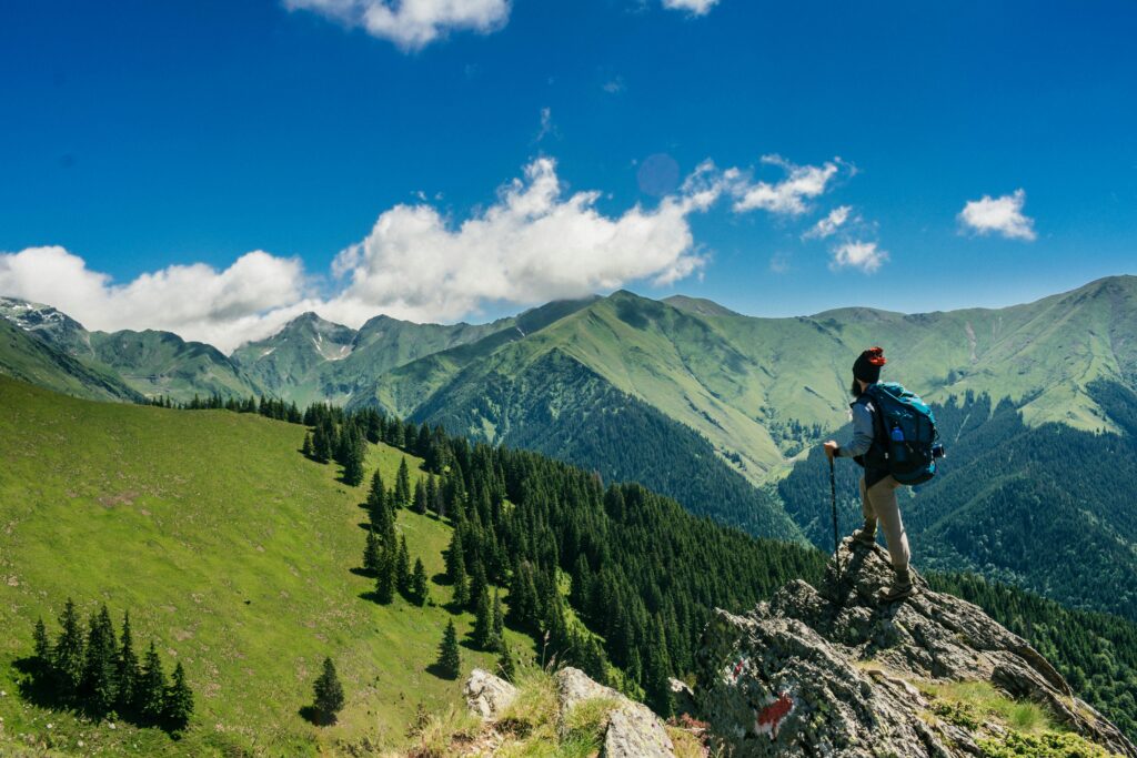 Image of a man hiking out to a cliff overlooking a green valley of trees. A valuable location can be helpful when promoting on experiential marketing. 