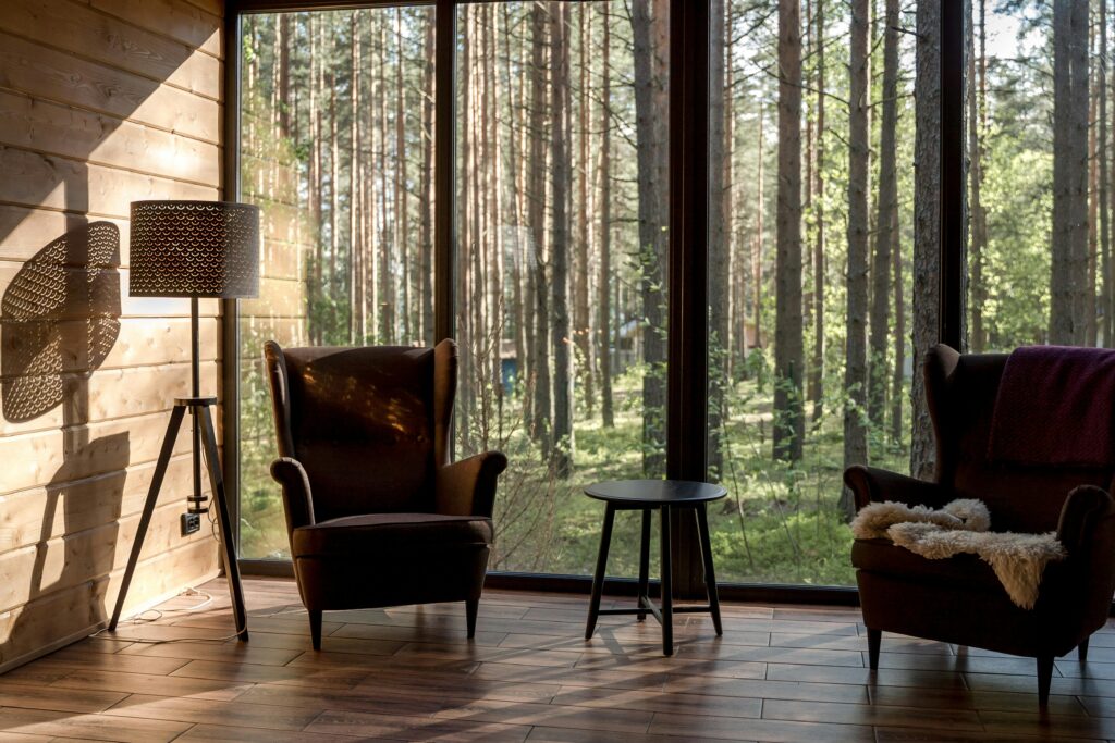 How does Airbnb compete with hotels? One way may be by offering unique amenities such as this sitting room adjacent to floor-length windows and a view of the serene woods. 